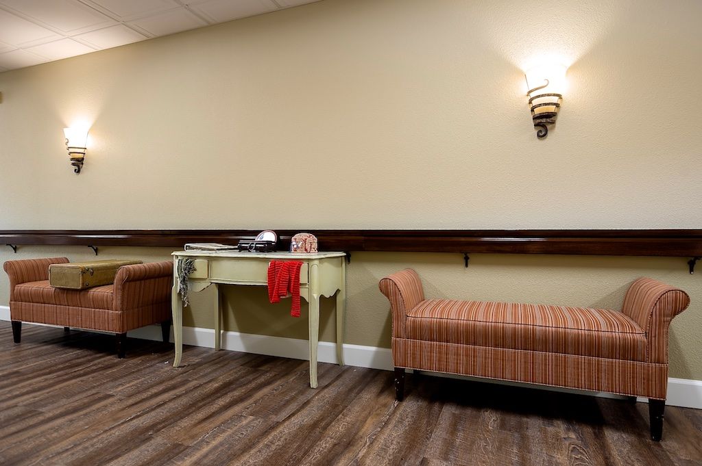 A cozy lobby area featuring a table between two striped benches, with a wall-mounted lamp providing ambient lighting.