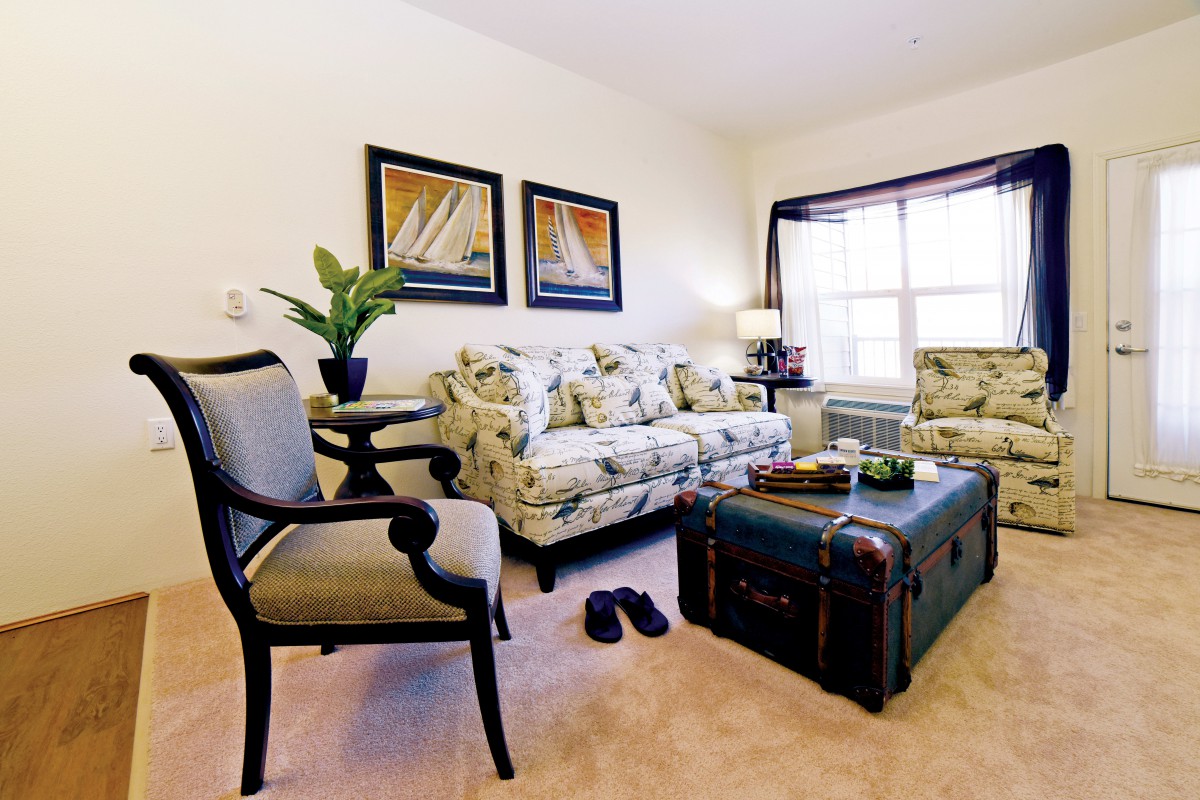 A cozy living room with floral sofas and nautical-themed artwork.