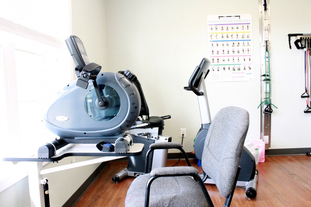 A small fitness room equipped with stationary bikes and office chairs.