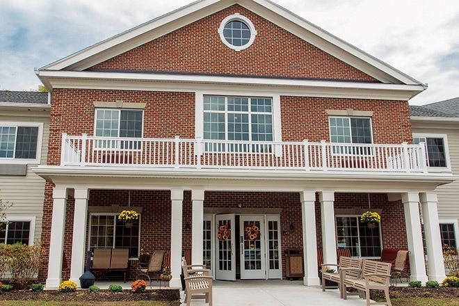 A two-story brick building with a porch and large windows.