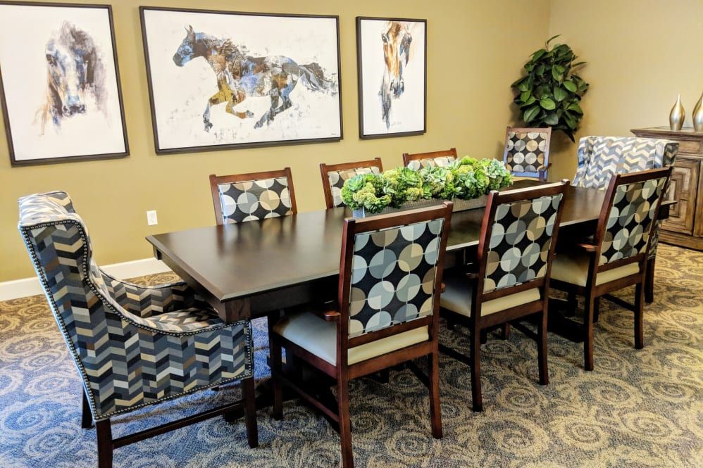 A dining area with a wooden table, patterned chairs, and horse-themed artwork on the walls.