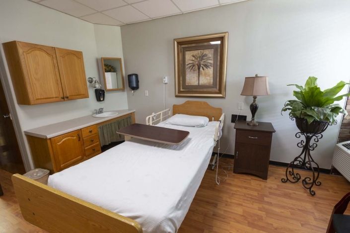A clean and well-organized hospital room with a single bed and cozy decor.
