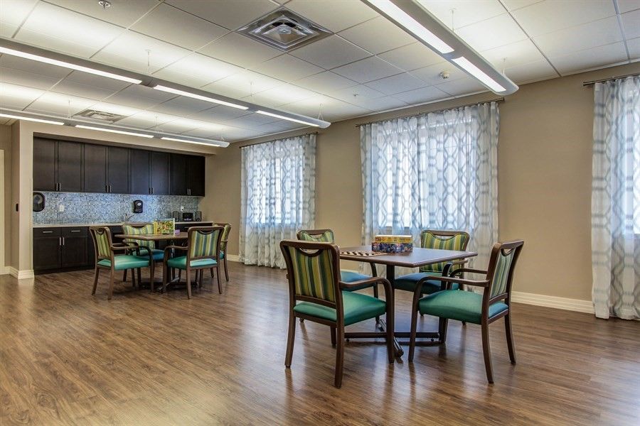 A well-lit dining room with tables and chairs set on a wooden floor.