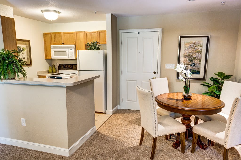 A cozy apartment kitchen with a dining area featuring a round wooden table and white chairs.
