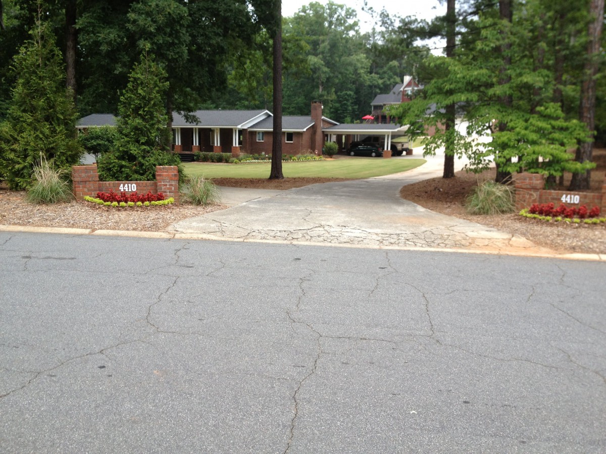 A suburban house with a driveway surrounded by trees and landscaping.
