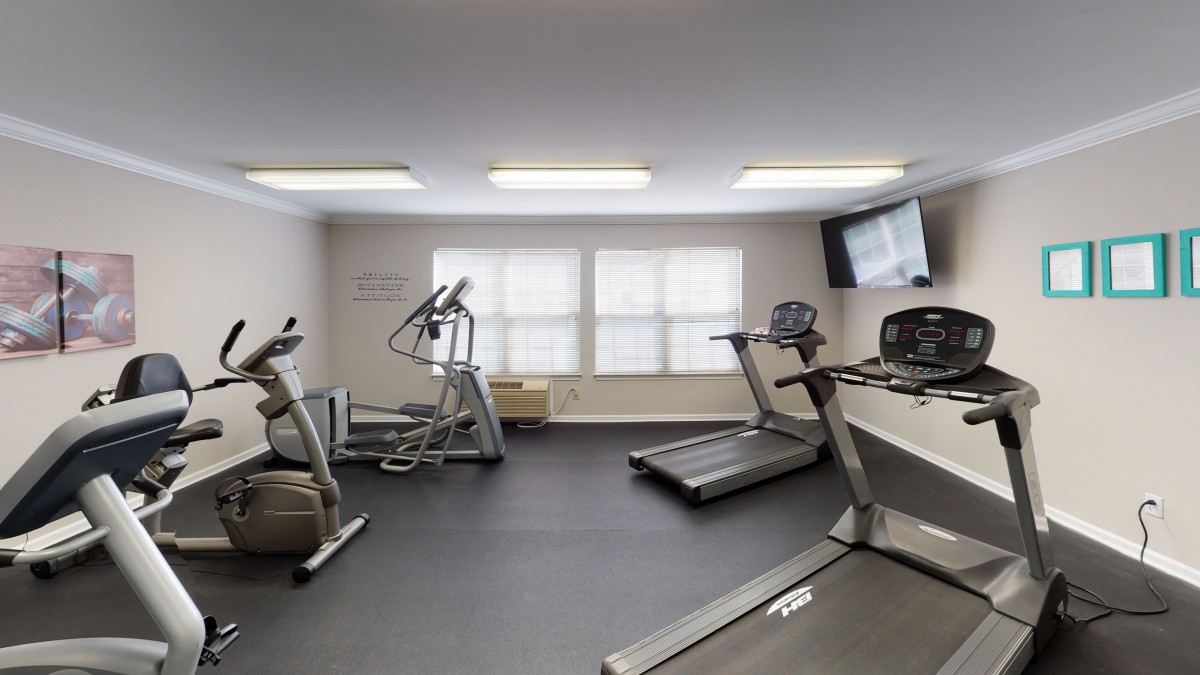 A modern gym with exercise equipment including treadmills and an elliptical machine.