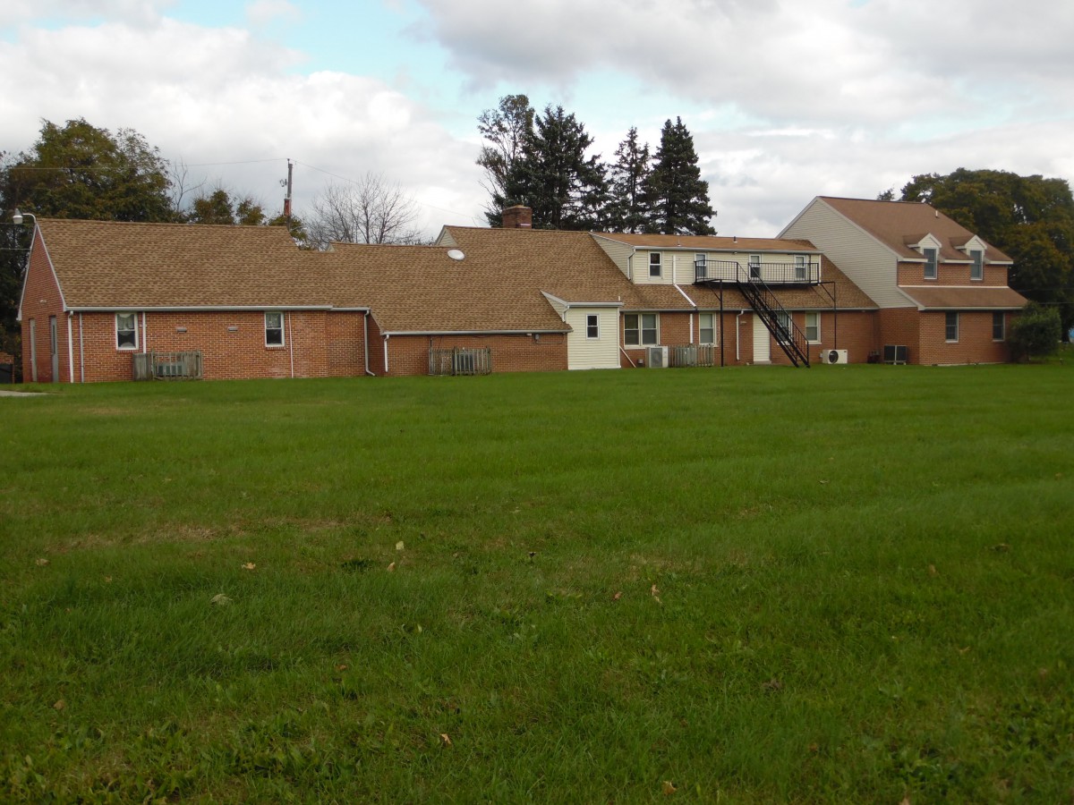A view of a residential complex with a large grassy field and cloudy sky.