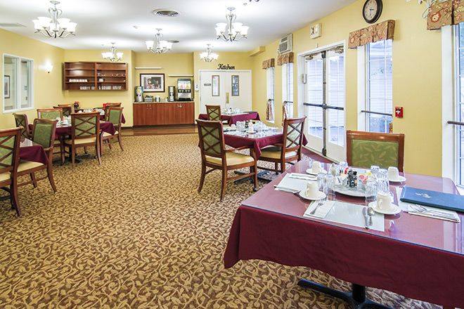 A well-lit dining area with tables and chairs arranged neatly, set with tableware and decorated with a warm color scheme.