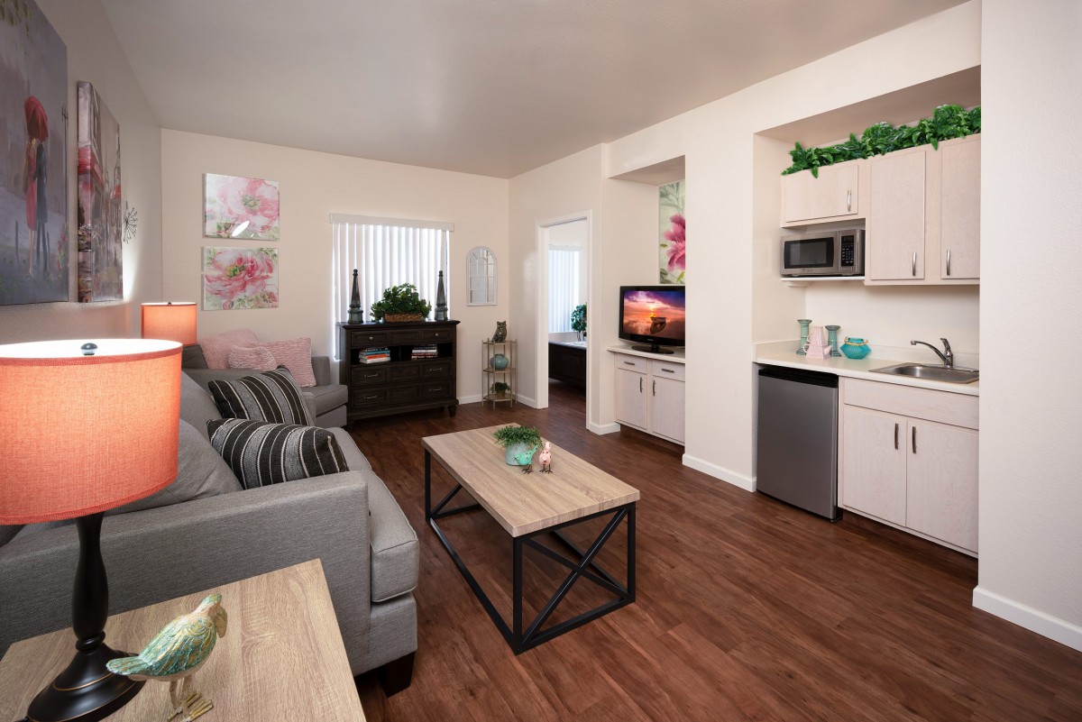 A cozy and modern living room with a comfortable sofa, coffee table, and a small kitchenette.