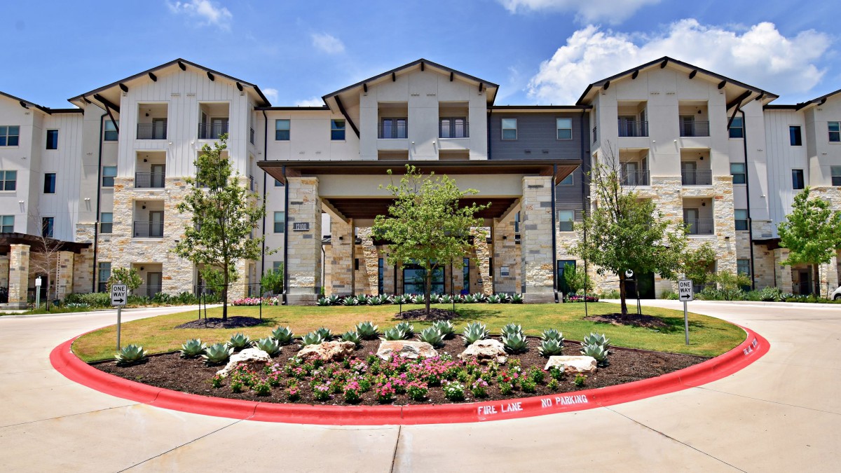 A modern residential building with landscaped gardens and a welcoming entrance.