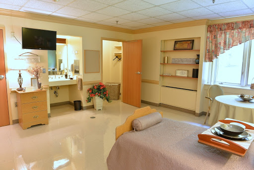 A well-equipped hospital patient room featuring a bed, furniture, and a clean bathroom area.