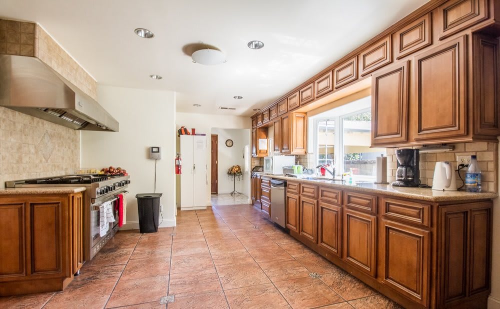 A spacious, modern kitchen with wooden cabinets and large windows.