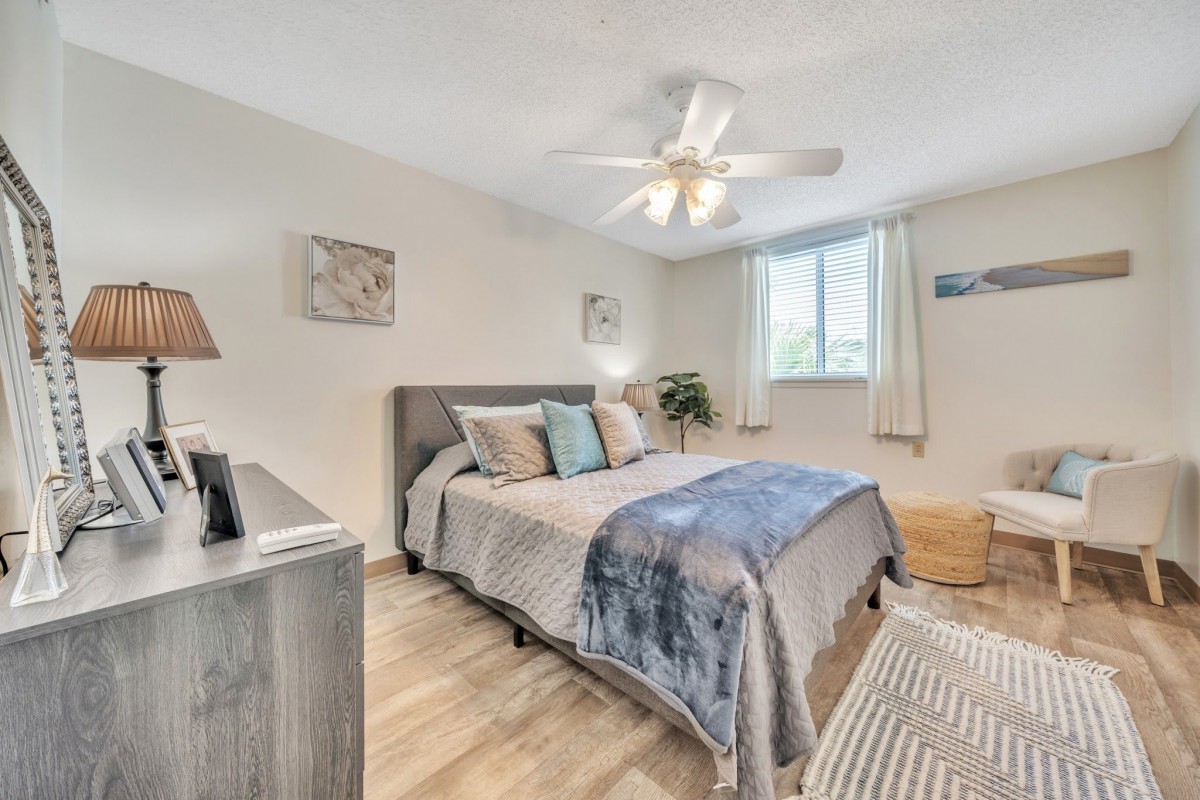 A modern bedroom with a comfortable bed, ceiling fan, and stylish decor.