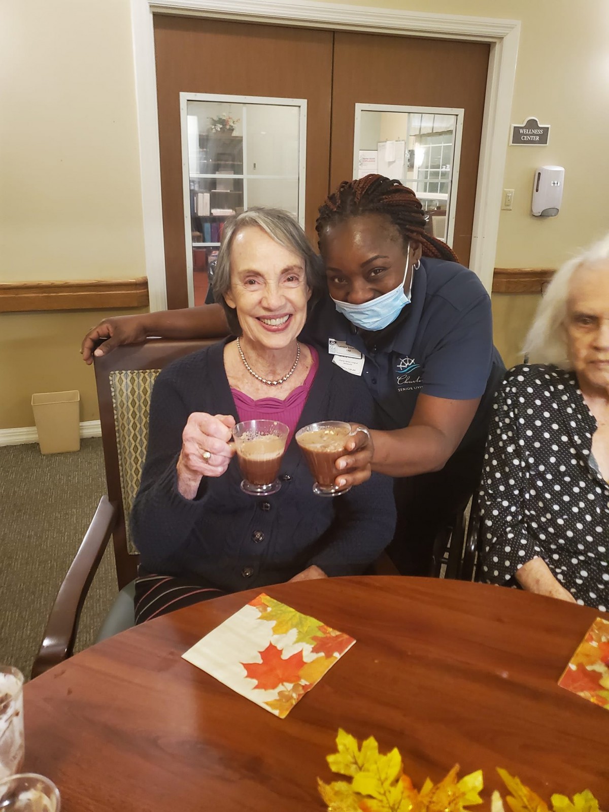 Elderly woman enjoying a coffee celebration with caregiver in a nursing home.