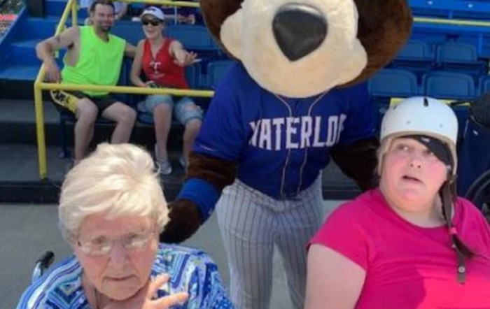 A mascot in a Waterloo jersey interacts with the audience at a baseball game.