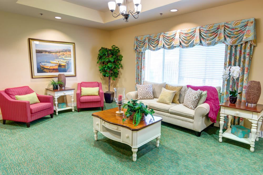 A cozy living room with a sofa, armchairs, and a coffee table on a green carpet.