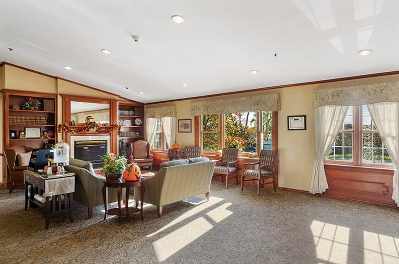 A cozy living room featuring a seating area with a fireplace and large windows.