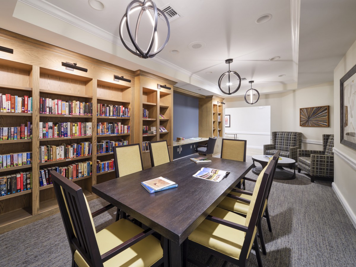 A modern library meeting room with bookshelves, a large table, and comfortable chairs.