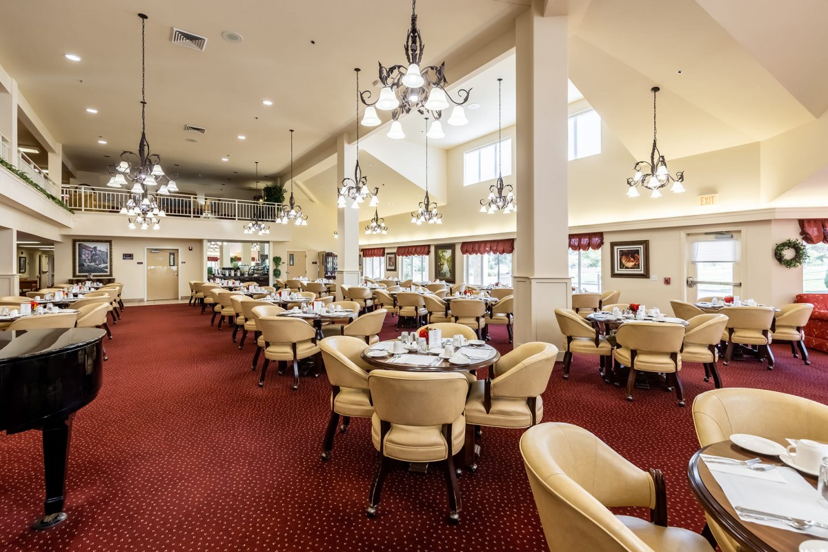 Spacious and elegantly designed dining area with chandeliers and neatly arranged tables.
