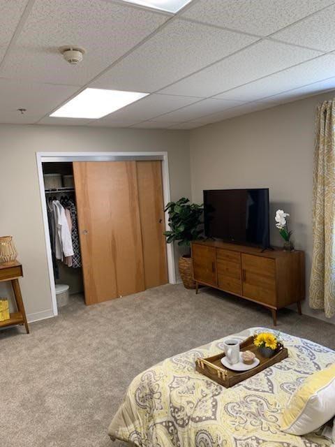 A cozy bedroom featuring a wooden dresser with a television and an open wardrobe.