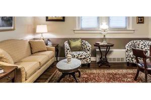 A cozy living room with a beige sofa, patterned armchair, and a coffee table, illuminated by table lamps.