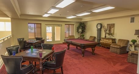 A cozy recreation room featuring a pool table and seating area, complete with red carpet and classic decor.