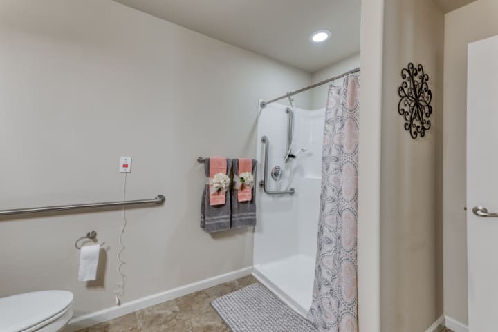 An accessible bathroom featuring a walk-in shower with grab bars and neatly arranged towels.