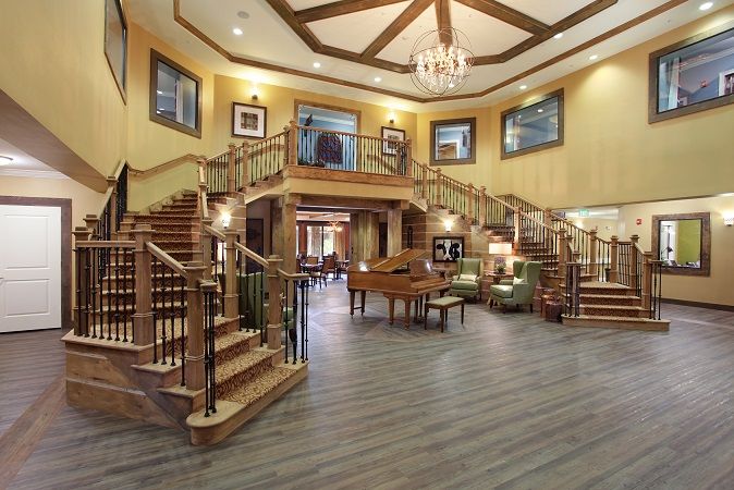 A luxurious grand entrance lobby featuring a double staircase, elegant chandelier, and cozy seating area.
