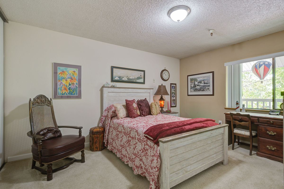 A cozy bedroom with a decorated bed, artwork on the walls, and a window providing natural light.