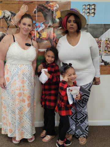 A family group photo featuring two adults and two children posing indoors.