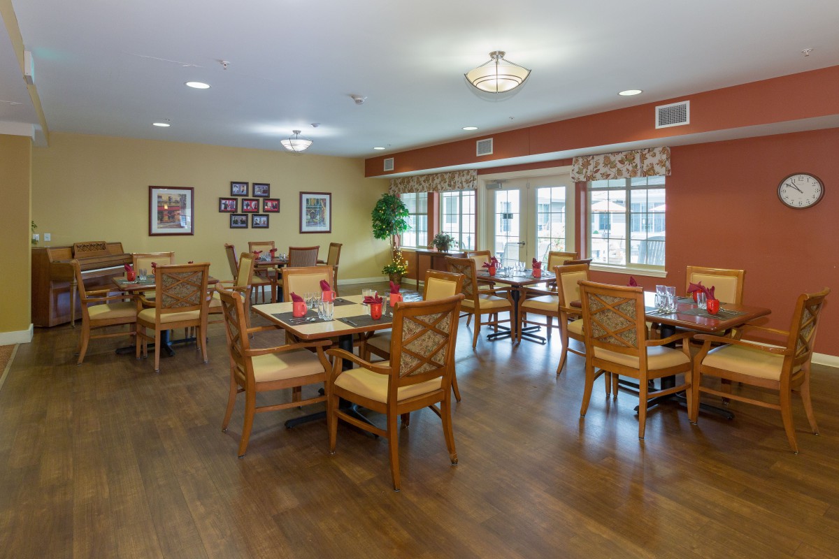 A spacious and well-lit dining room with multiple tables and chairs, featuring wooden flooring and stylish decor.