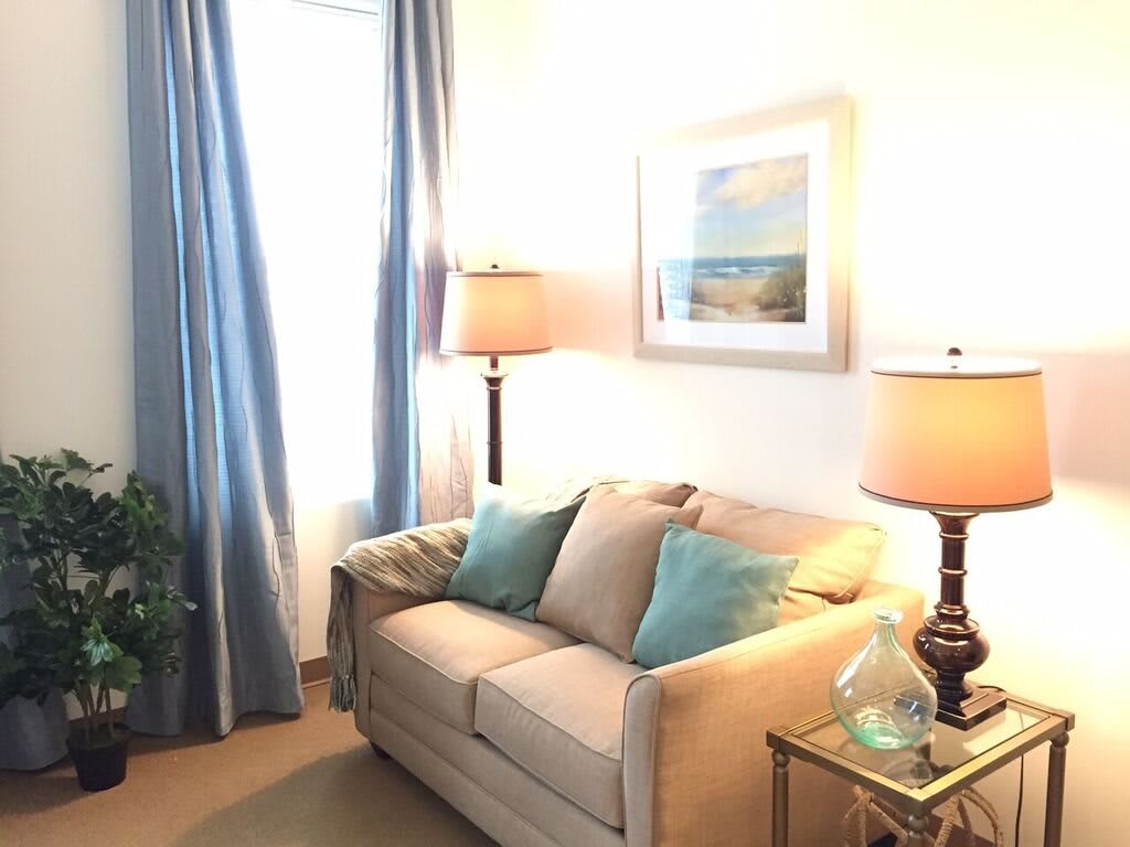 A cozy living room with a beige sofa, blue cushions, and warm lighting.