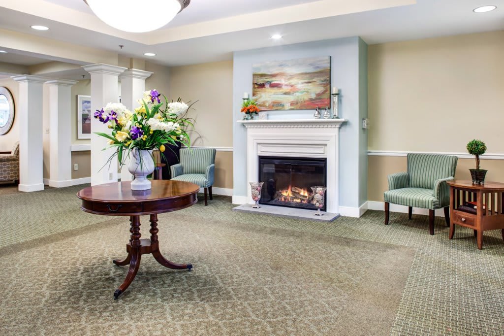A cozy living room with a fireplace and decorative flowers.