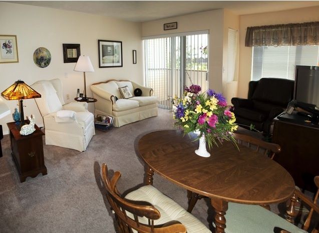A cozy living room with a dining area, featuring comfortable seating and floral decor.