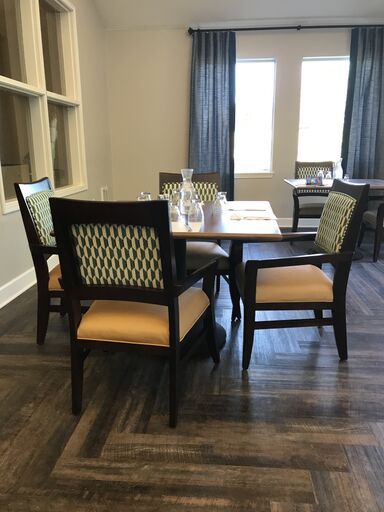 A neatly set dining table with four chairs in a well-lit restaurant interior.