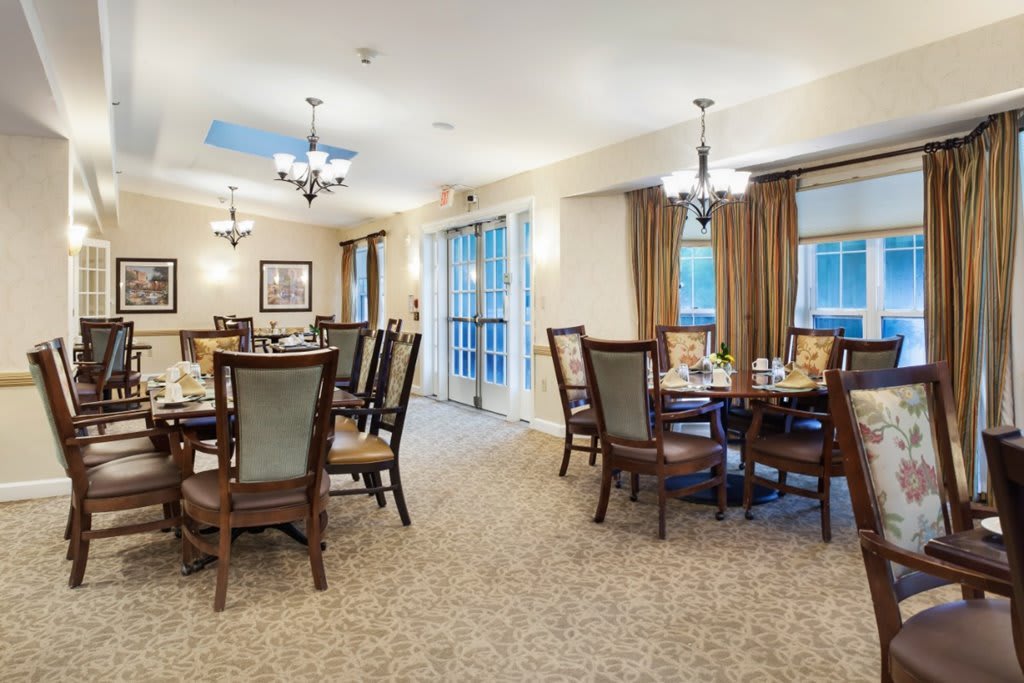 A spacious dining area with elegant tables and chairs, adorned with chandeliers and large windows.