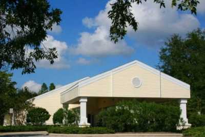 A church building with a bright, clear sky and surrounding greenery.