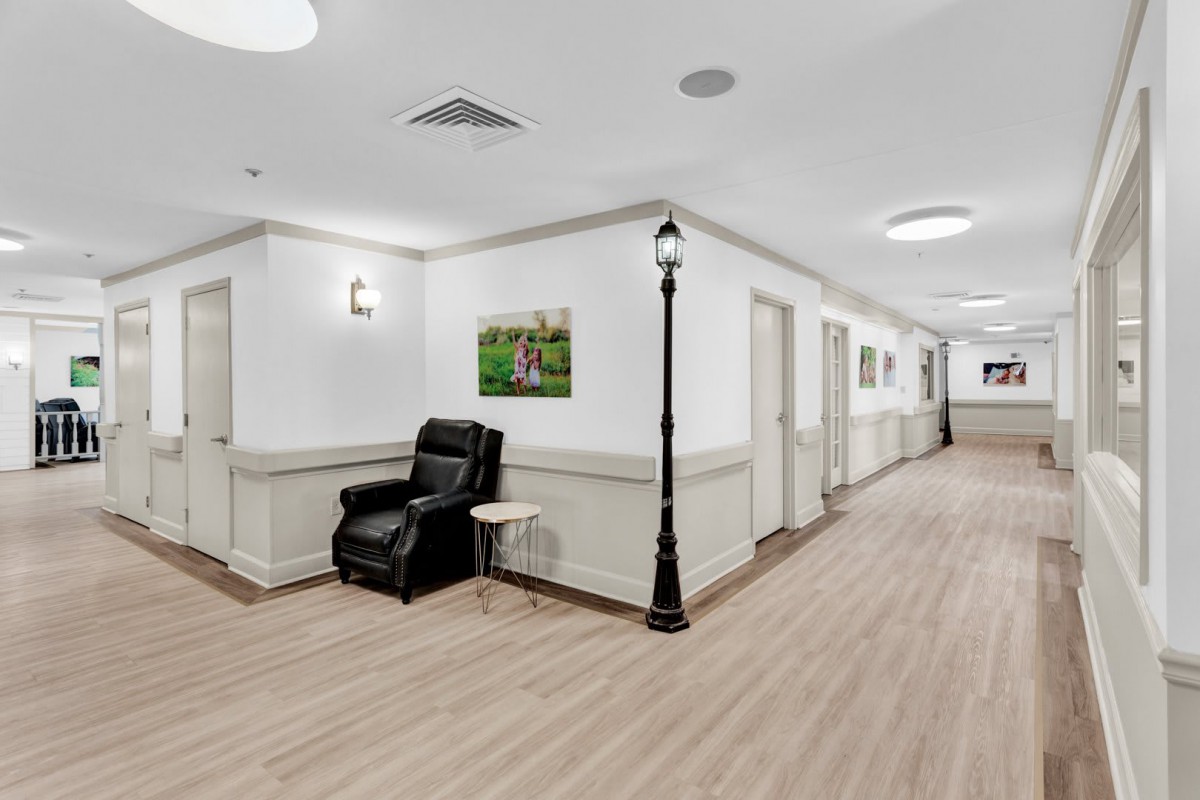 A clean and well-lit hallway featuring a comfortable chair and decorative lamp post.