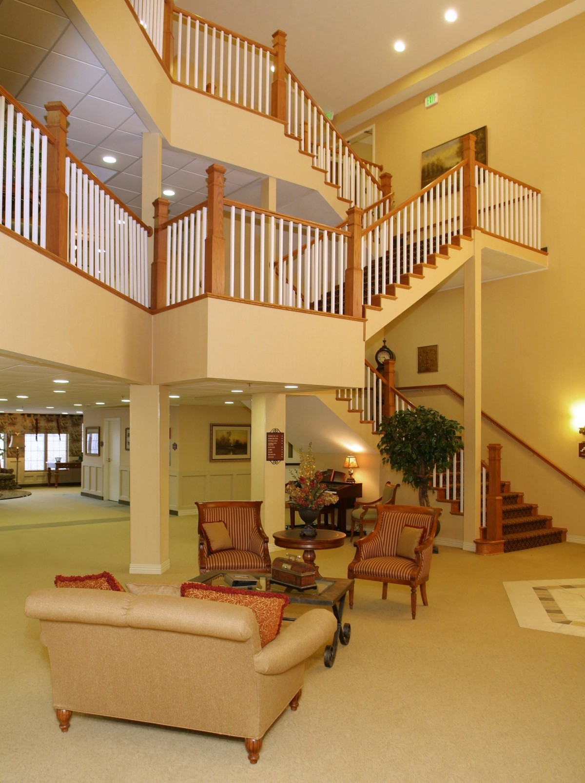 A spacious living room with a grand staircase and comfortable seating.