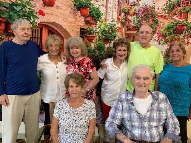 A cheerful group of people gathered together in a floral setting.