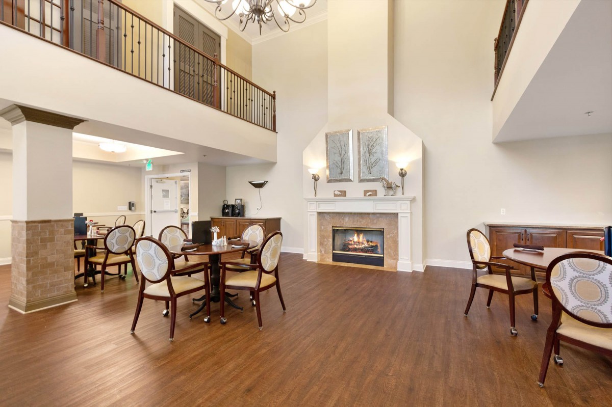 A spacious living area featuring a fireplace and dining setup with elegant furniture and high ceilings.