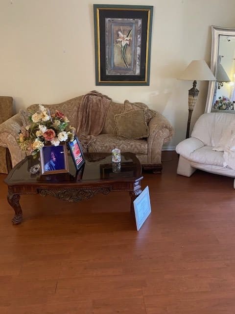 A cozy living room with a sofa, coffee table with flowers, and a painting on the wall.
