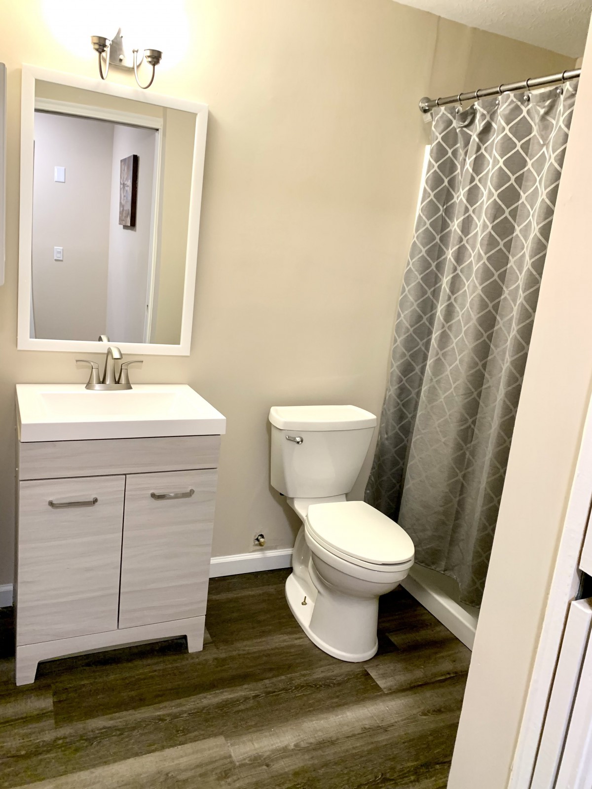A modern bathroom with a vanity, toilet, and patterned shower curtain.