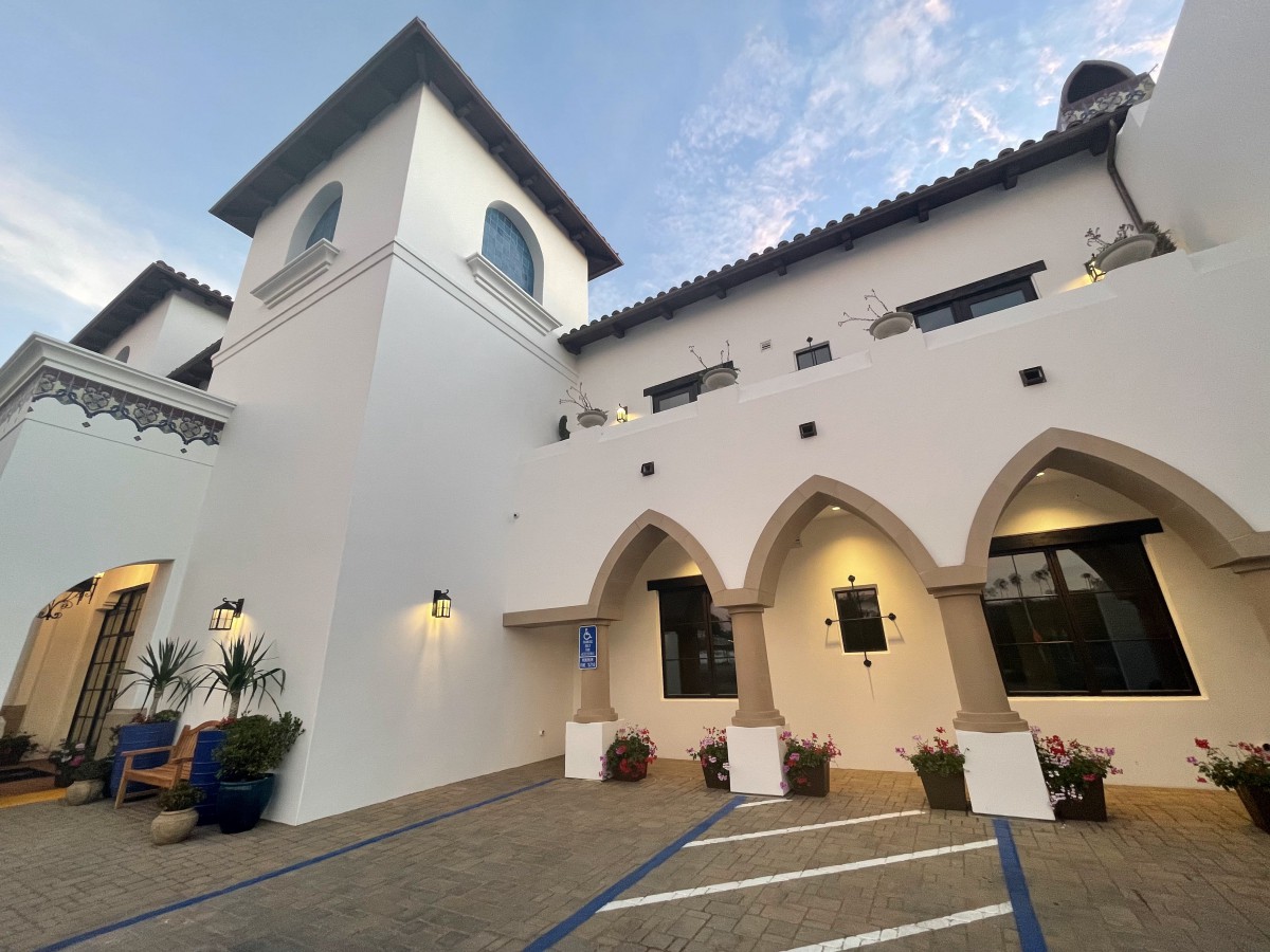 A Mediterranean-style building with arched windows and a tower, featuring a white exterior and outdoor lighting.
