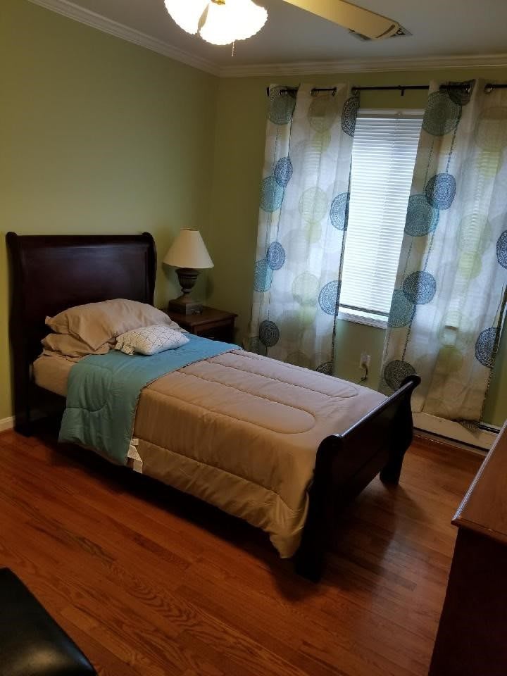 A cozy bedroom with a single bed, bedside lamp, and patterned curtains.