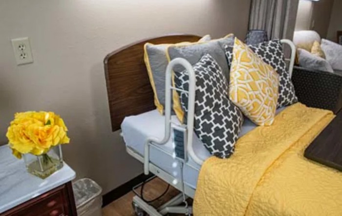 A decorated hospital bed with yellow and patterned pillows.