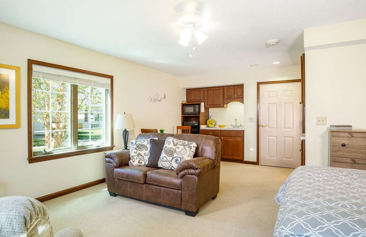 A cozy living room with a leather sofa and adjacent kitchenette.