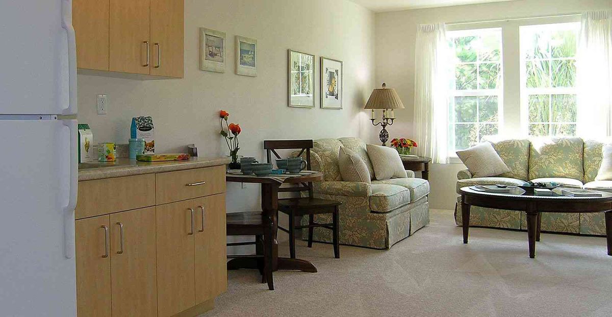 A cozy living room with light-colored furniture and a large window letting in natural light.