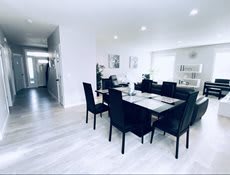A modern and minimalist dining room with a sleek table and chairs set, featuring bright lighting and contemporary decor.