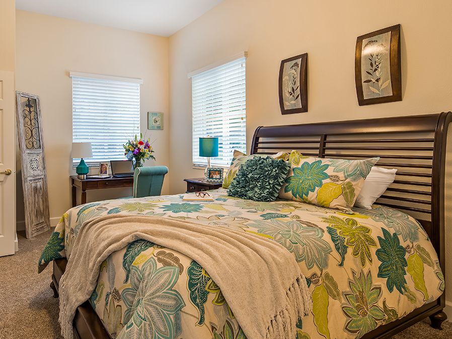 A cozy bedroom with floral bedding and bright natural light.